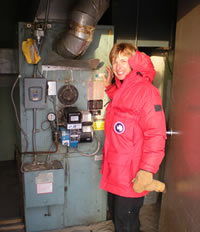 Carol Fey checking a furnace.  Carol's expertise is in heating and air conditioning, as well as wiring and circuits.